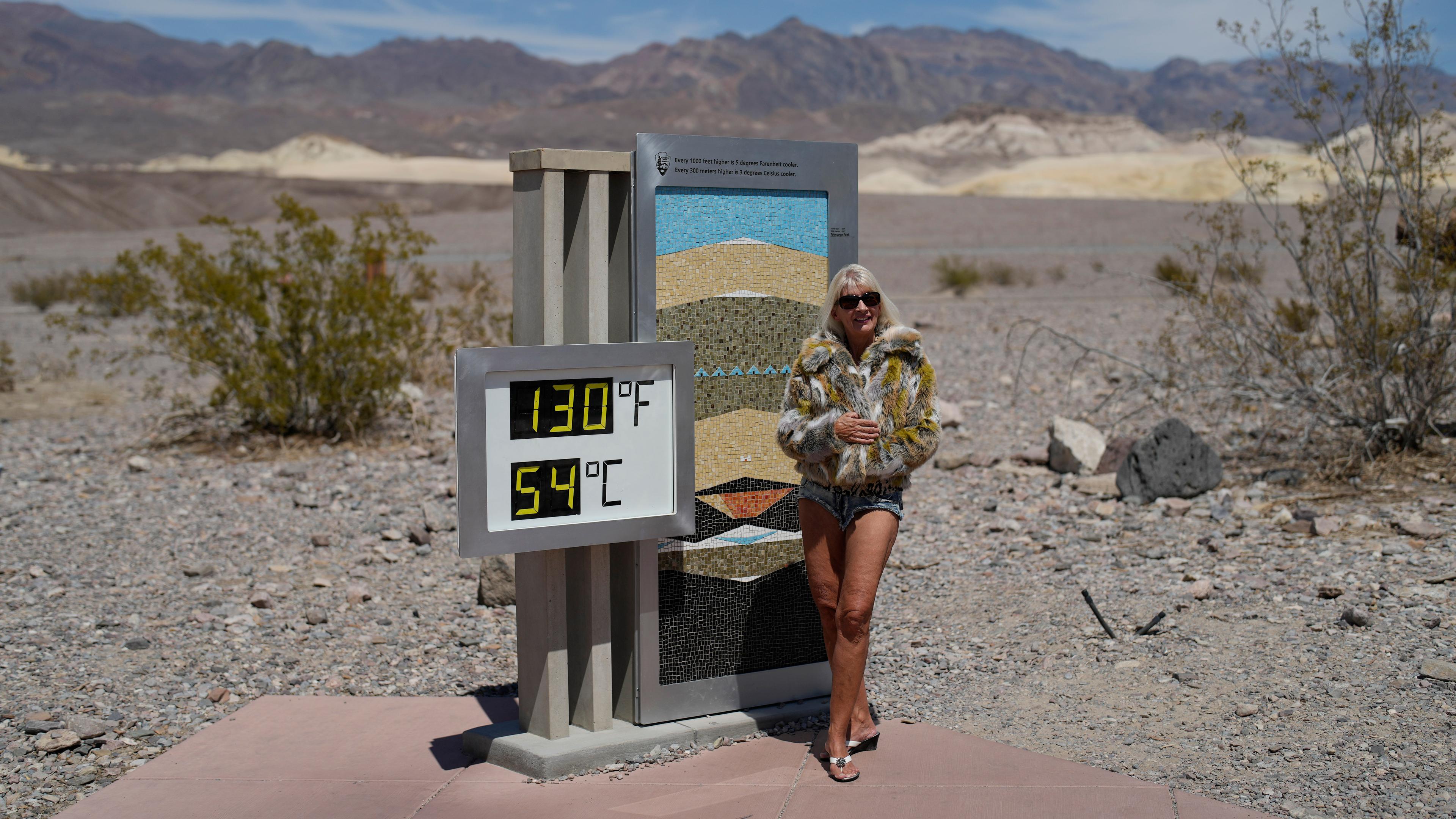 Eine Frau steht neben einem Schild: 54 Grad im Death Valley, USA.