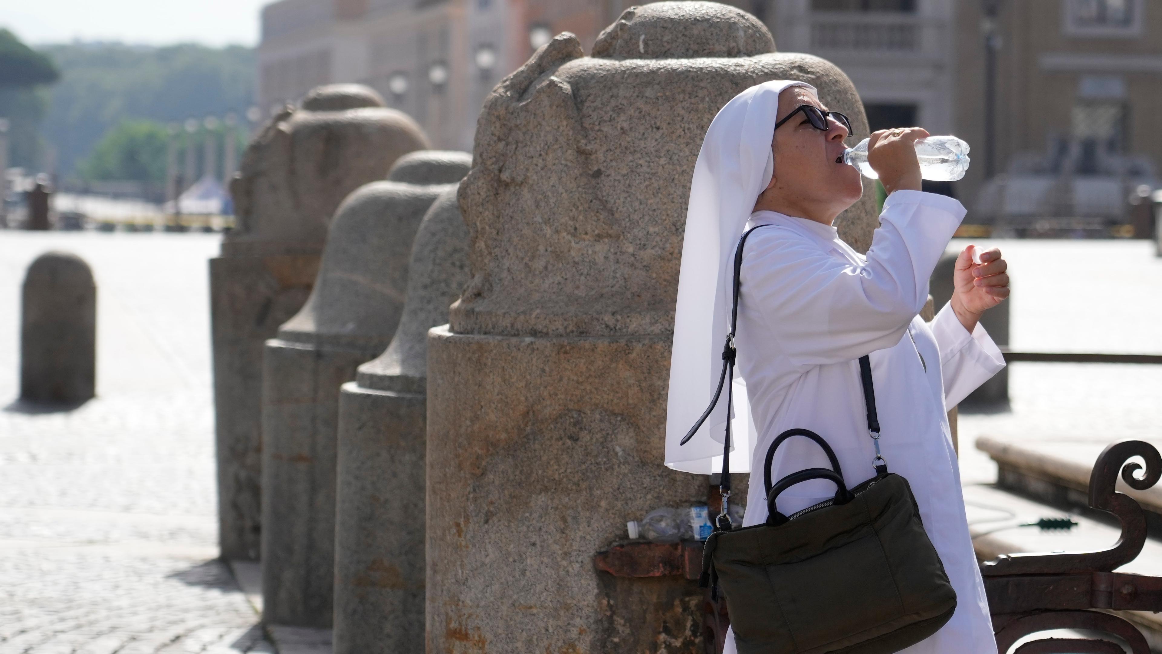 Eine Nonne trinkt aus einer Wasserflasche auf dem Petersplatz.