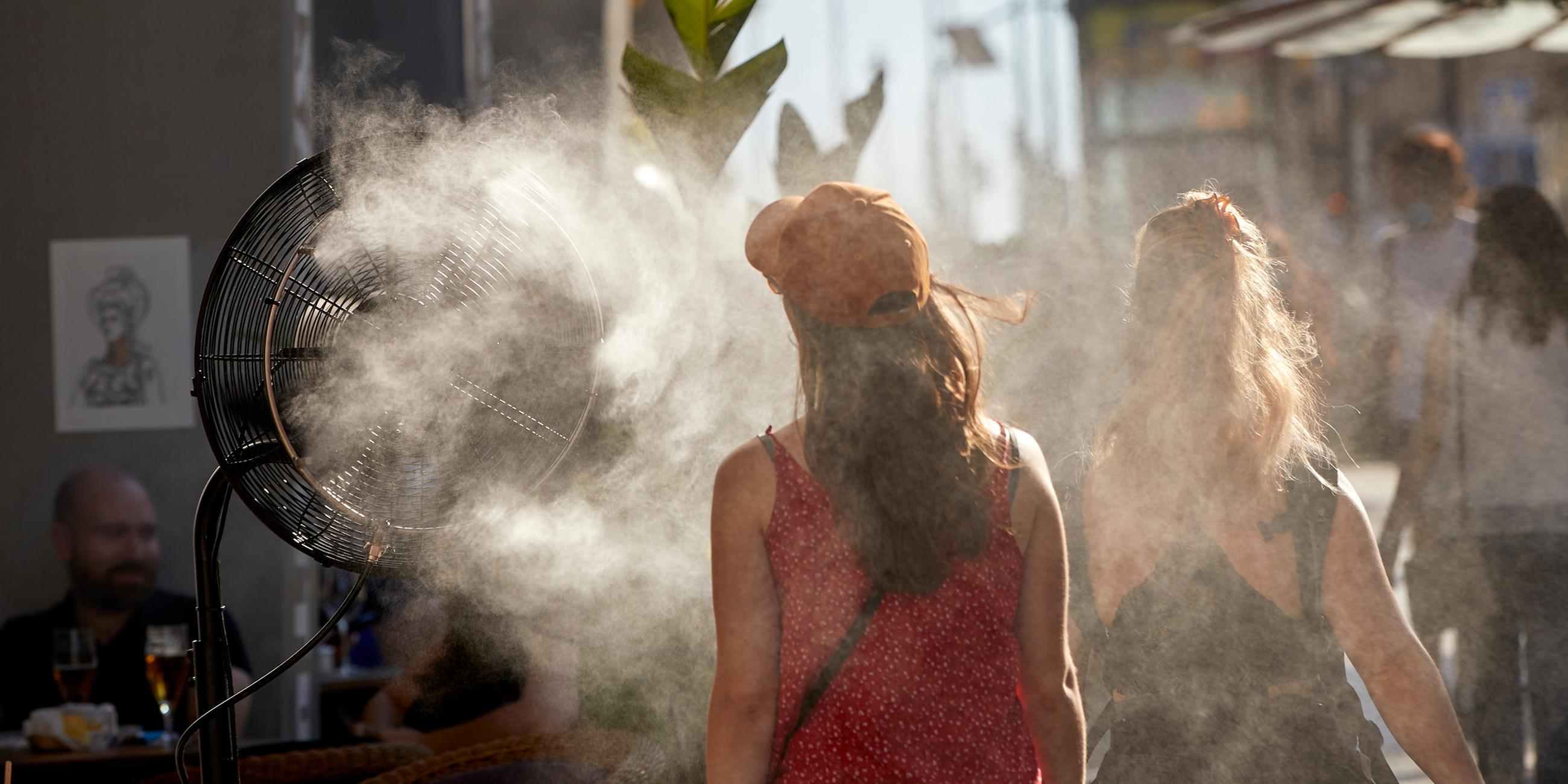 Spanien, Madrid: Eine Frau kühlt sich vor der Hitze mit einem Wasserdampfdiffusor ab