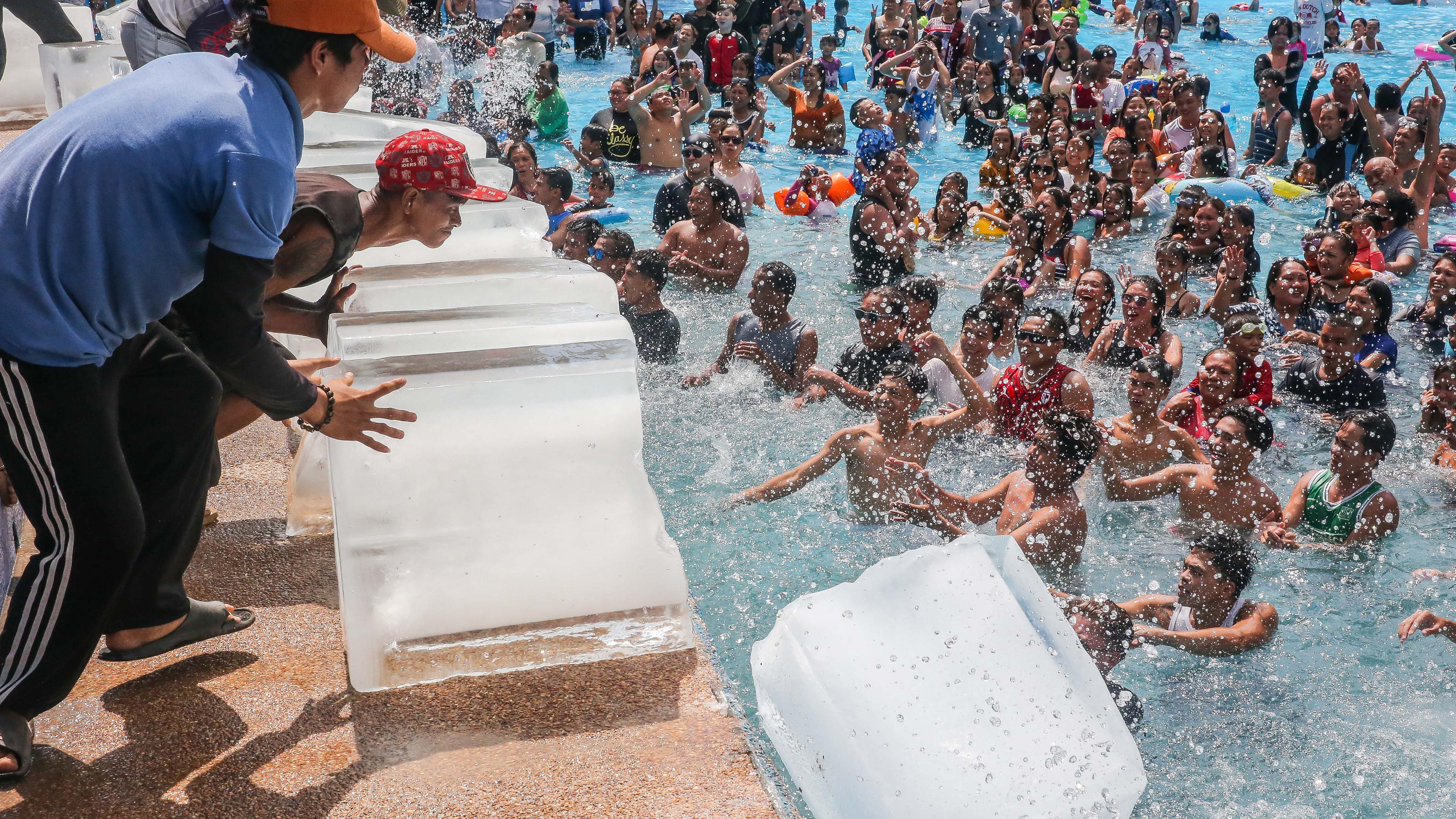 Philippinen, Bulacan: Mitarbeiter schieben Eisblöcke in einen Swimmingpool in einem Resort