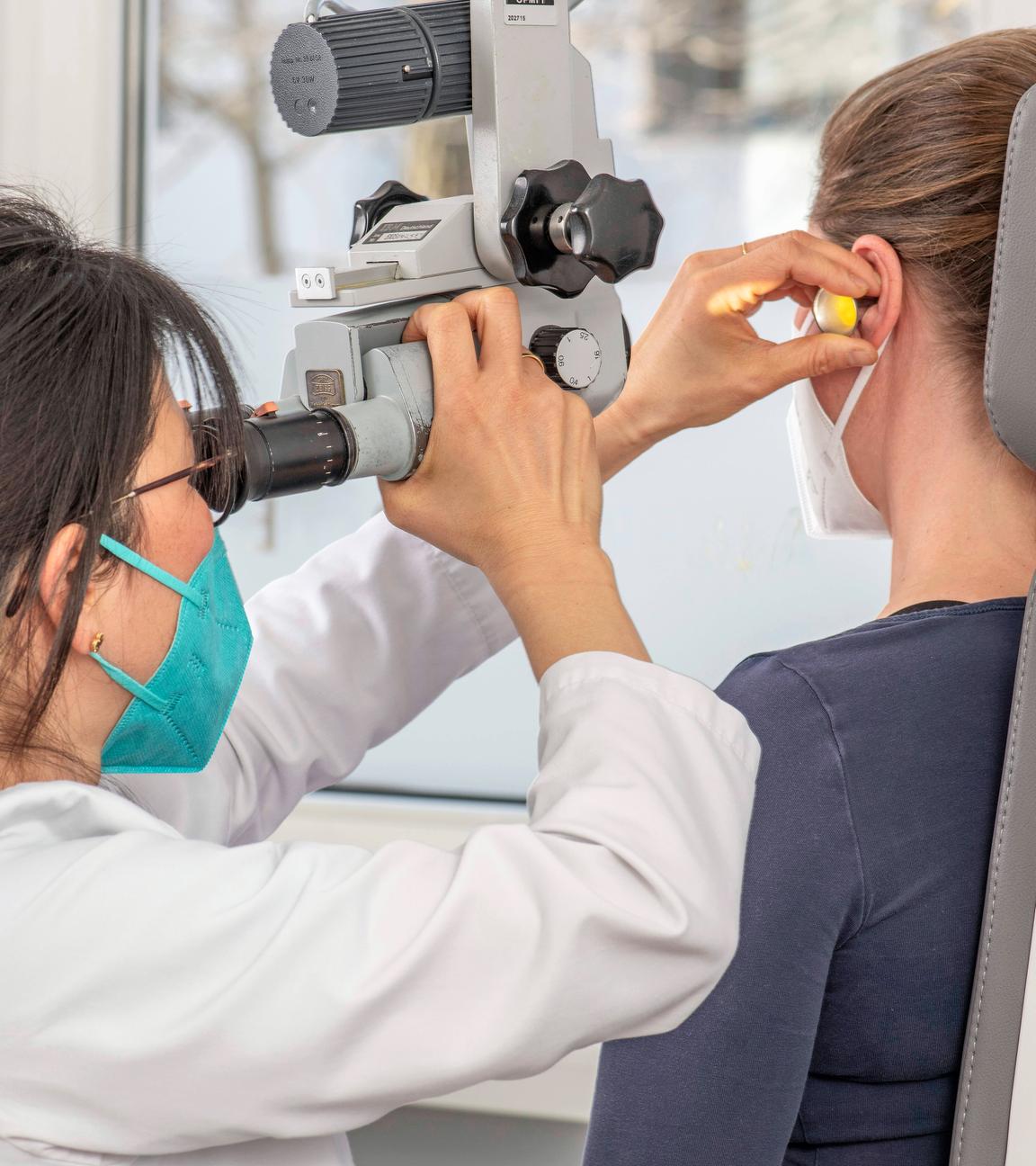 HNO-Fachärztin untersucht mit einem Mikroskop das Ohr einer Patientin, aufgenommen am 08.04.2022 in München, 