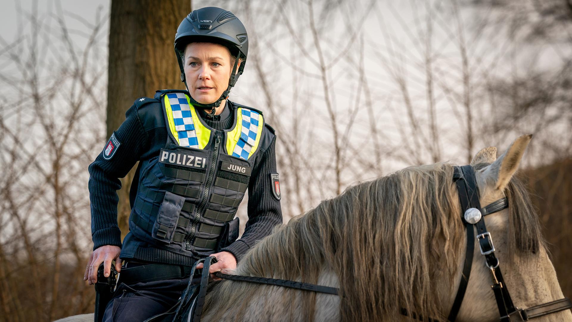 "Notruf Hafenkante - Hoch zu Ross": Großaufnahme von Franzi (Rhea Harder-Vennewald), die auf dem Rücken eines Pferdes sitzt. Ihre rechte Hand liegt auf ihrer Waffe, die im Halfter steckt.