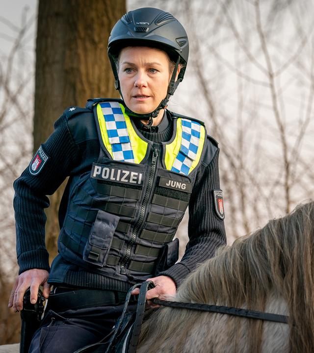 "Notruf Hafenkante - Hoch zu Ross": Großaufnahme von Franzi (Rhea Harder-Vennewald), die auf dem Rücken eines Pferdes sitzt. Ihre rechte Hand liegt auf ihrer Waffe, die im Halfter steckt.