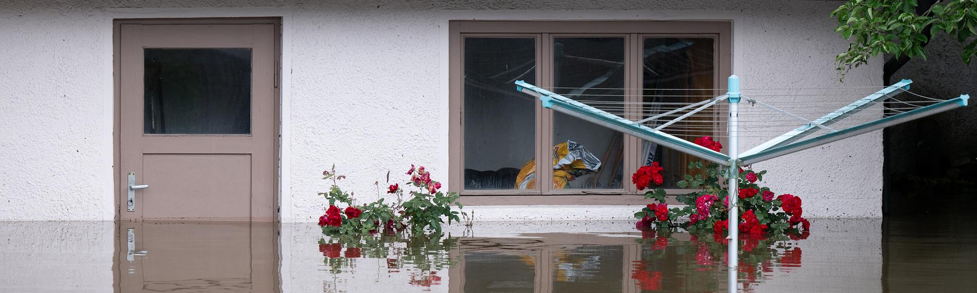 Ein Wäscheständer steht in einem überfluteten Garten von einem Wohnhaus
