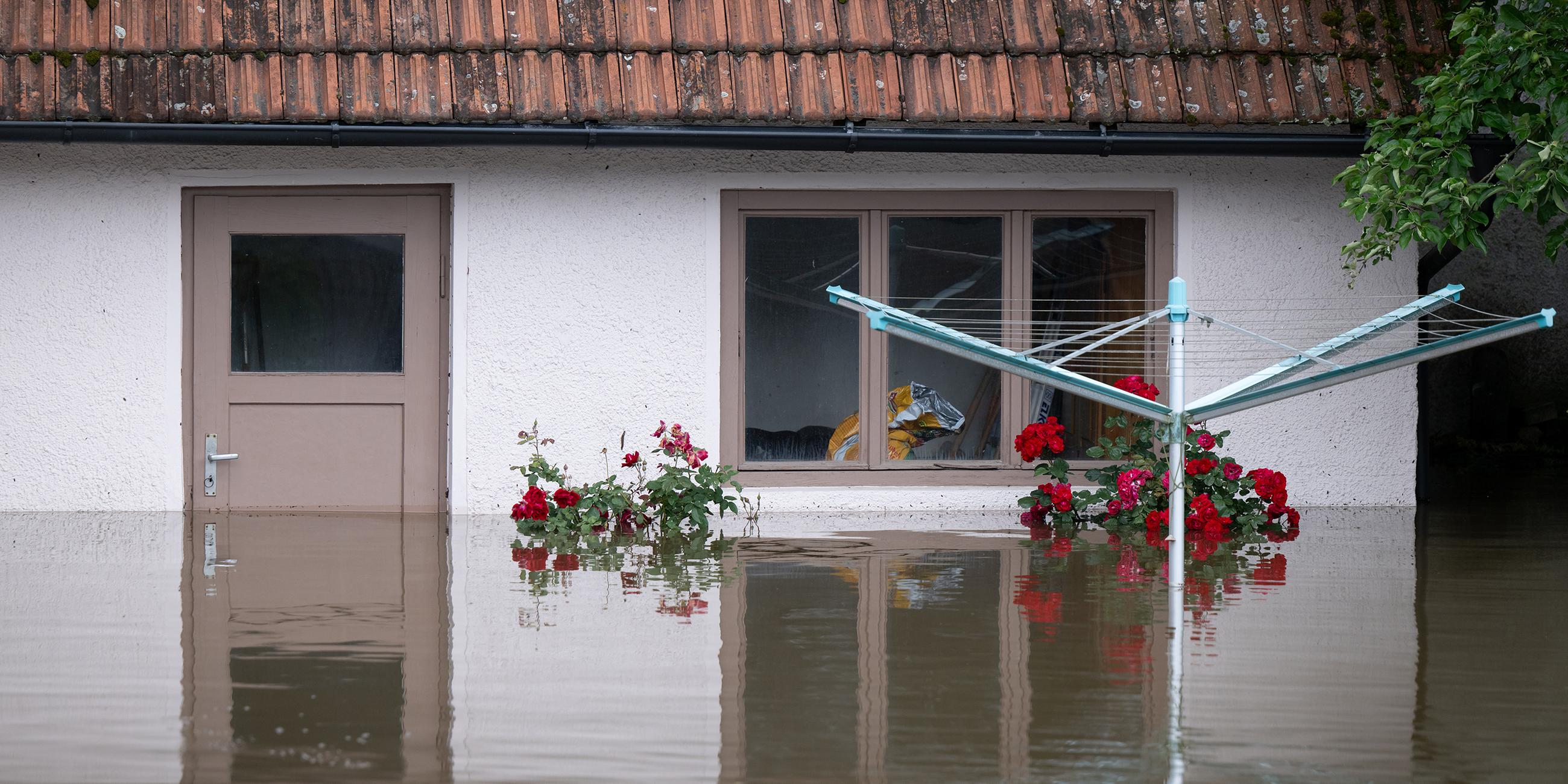 Ein Wäscheständer steht in einem überfluteten Garten von einem Wohnhaus