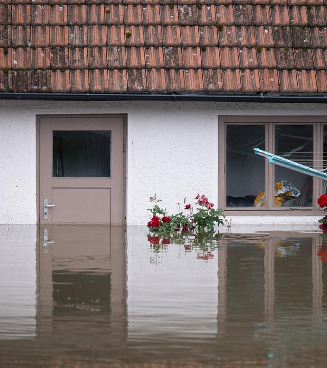 Ein Wäscheständer steht in einem überfluteten Garten von einem Wohnhaus