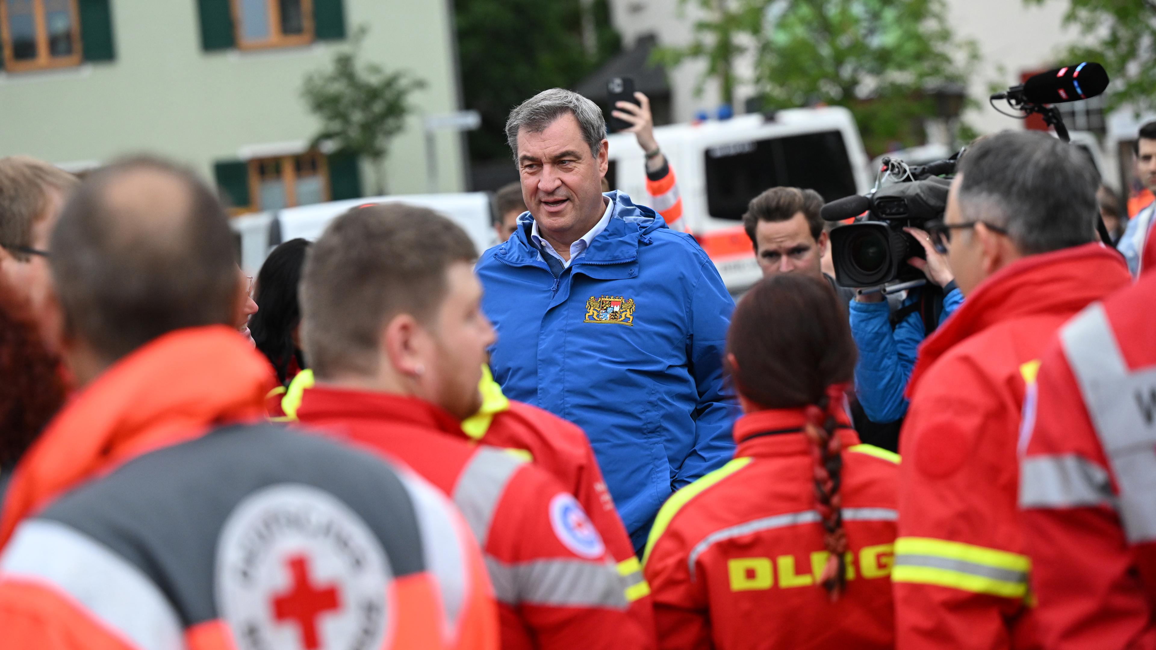 Bayern, Reichertshofen: Bayerns Ministerpräsident Markus Söder (M, CSU) spricht zu Einsatzkräften verschiedener Rettungsdienste bei einer Ortsbesichtigung im vom Hochwasser betroffenen oberbayerischen Reichertshofen.
