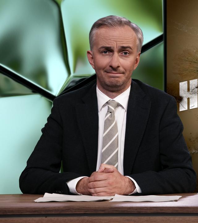 Jan Böhmermann sitzt am Schreibtisch. Rechts neben ihm steht das Wort "Hochwasser".