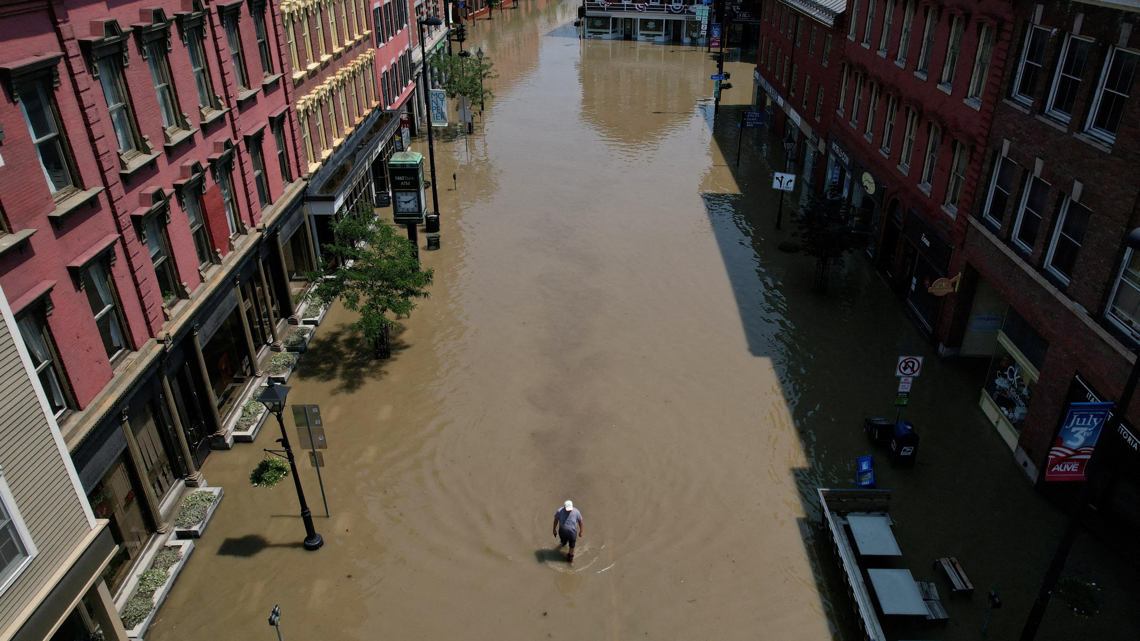 Ein Mann geht eine Straße entlang, die durch die jüngsten Regenstürme in Montpelier, Vermont, USA, überflutet wurde.