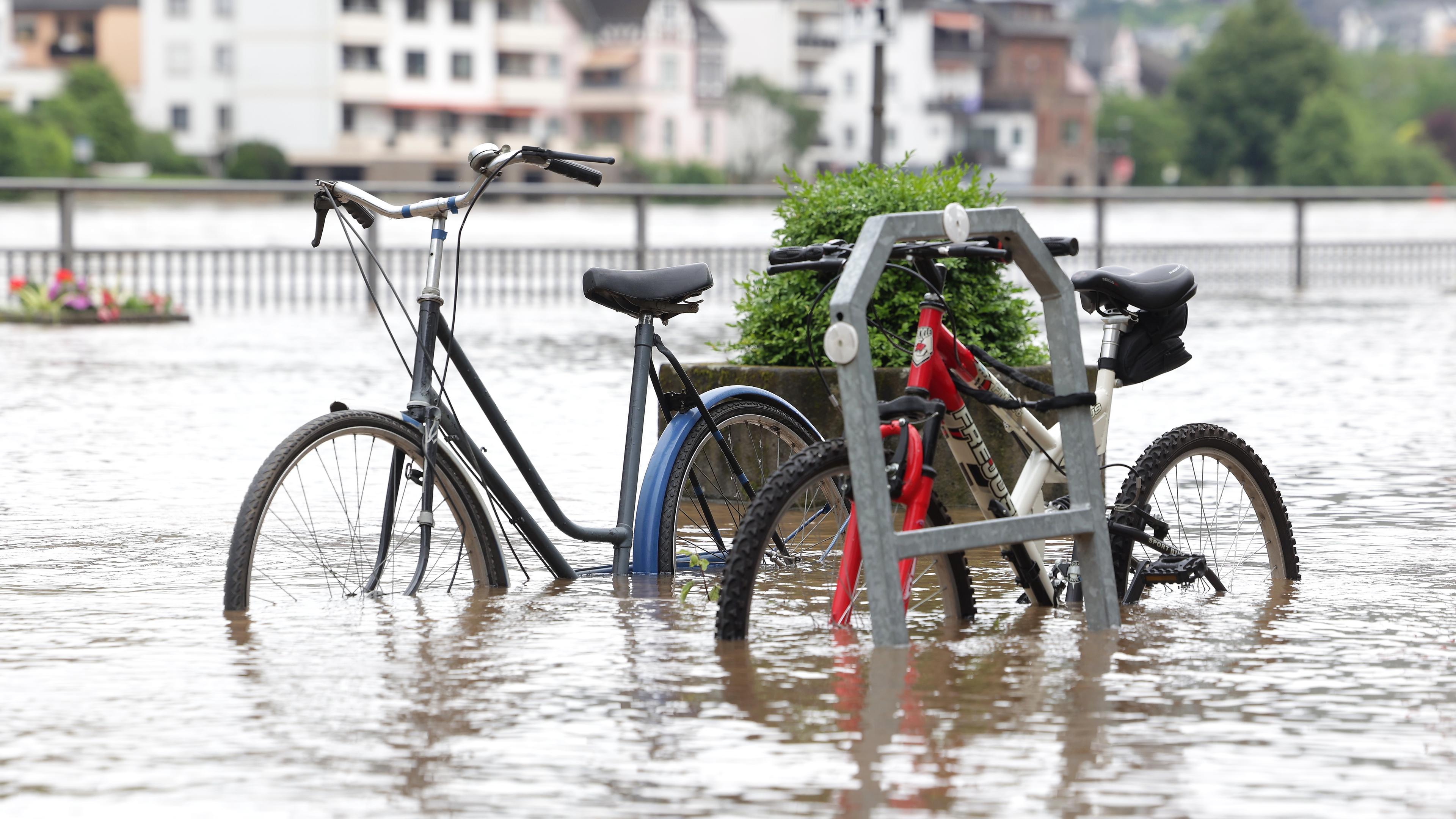 Rheinland-Pfalz, Cochem: Fahrräder stehen im Wasser auf der überfluteten Promenade an der Mosel. Heftiger Dauerregen hat Flüsse über die Ufer treten lassen und Überschwemmungen verursacht. 