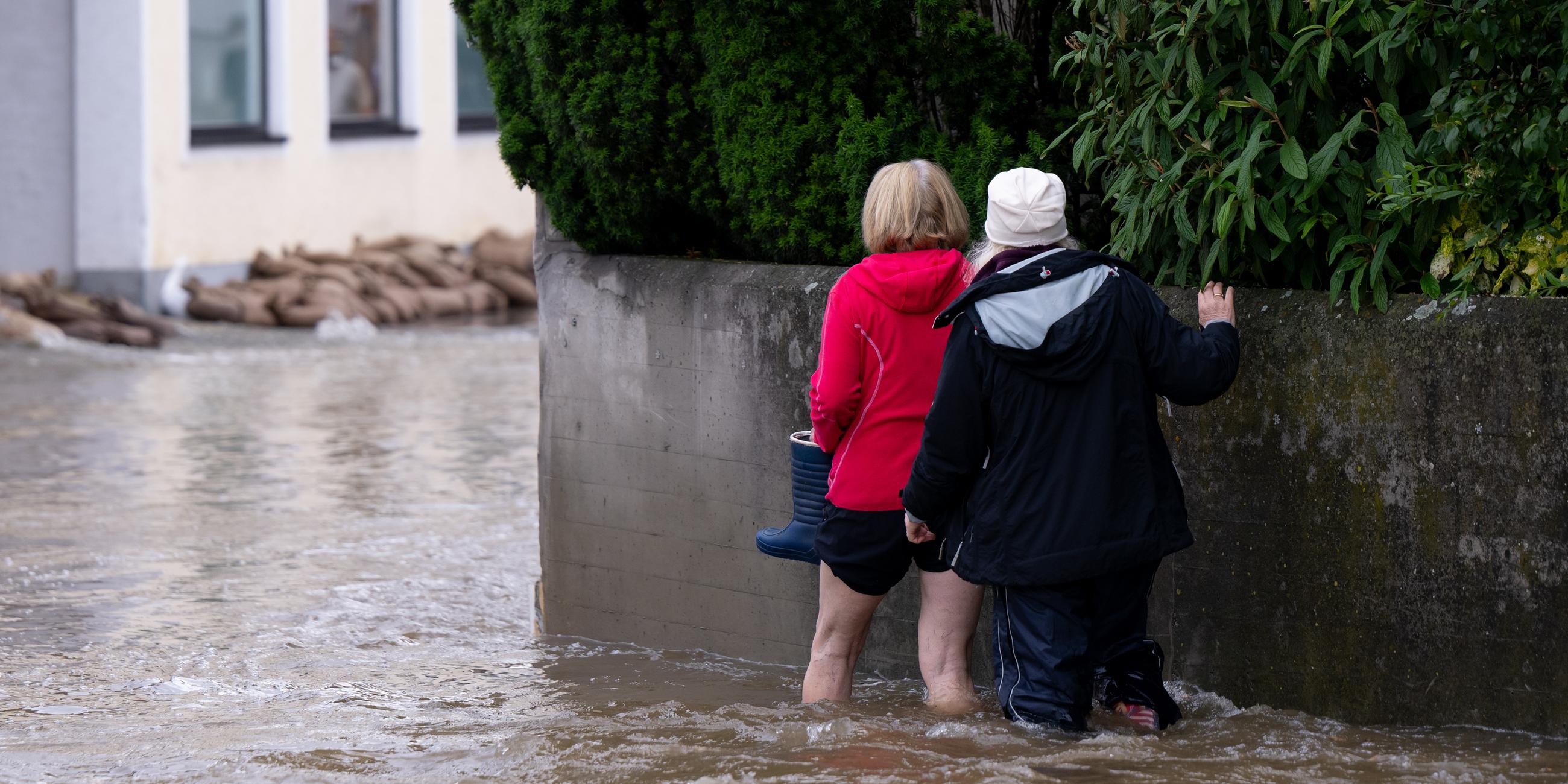 Zwei Frauen gehen durch überflutete Straßen