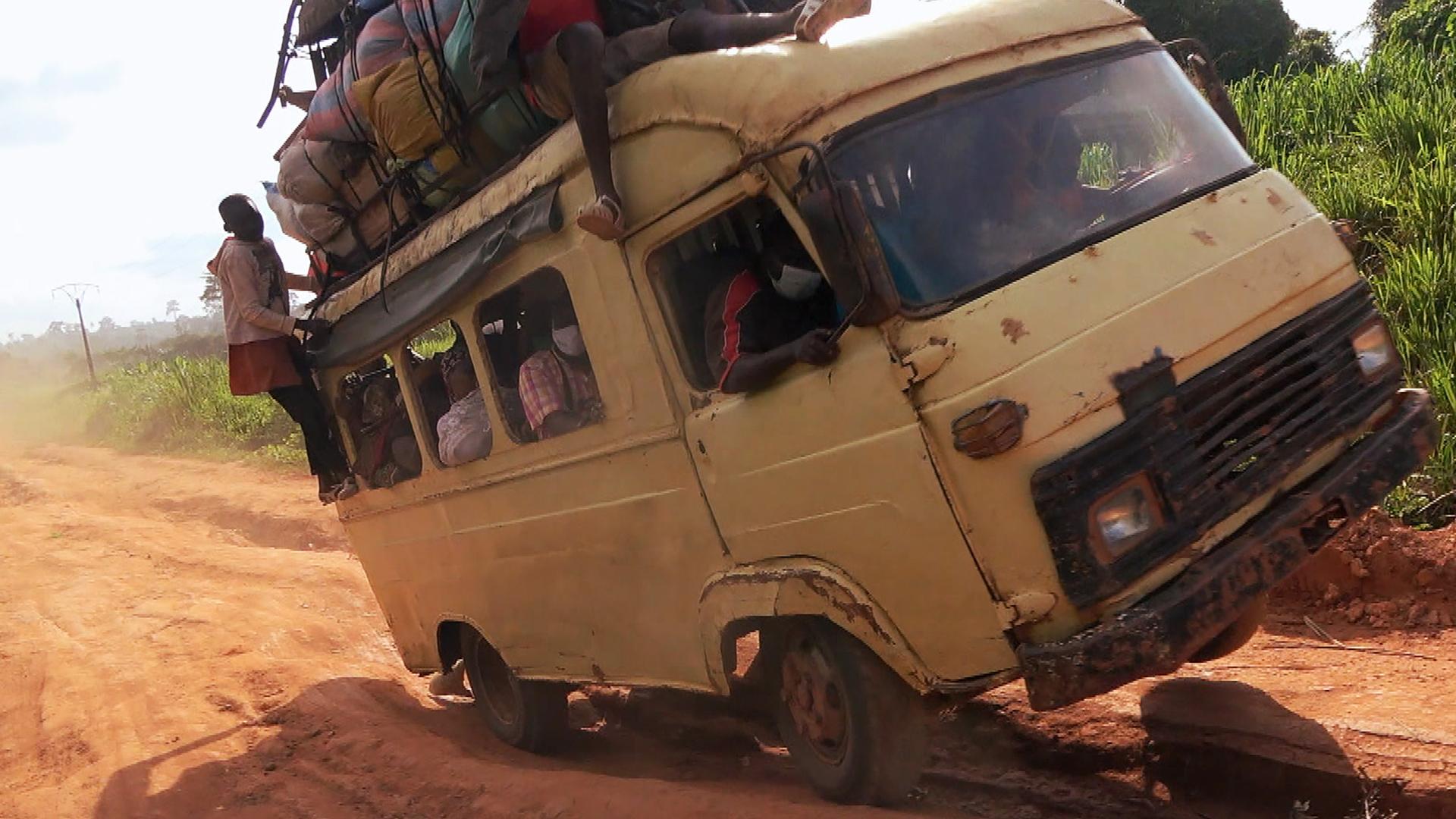 Ein weißer Laster mit Passagieren ist auf einer Straße in Schieflage geraten.