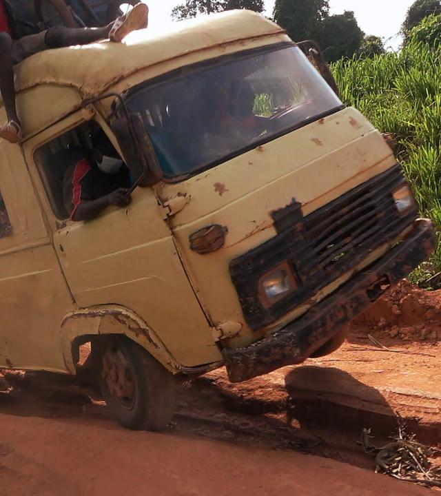 Ein weißer Laster mit Passagieren ist auf einer Straße in Schieflage geraten.