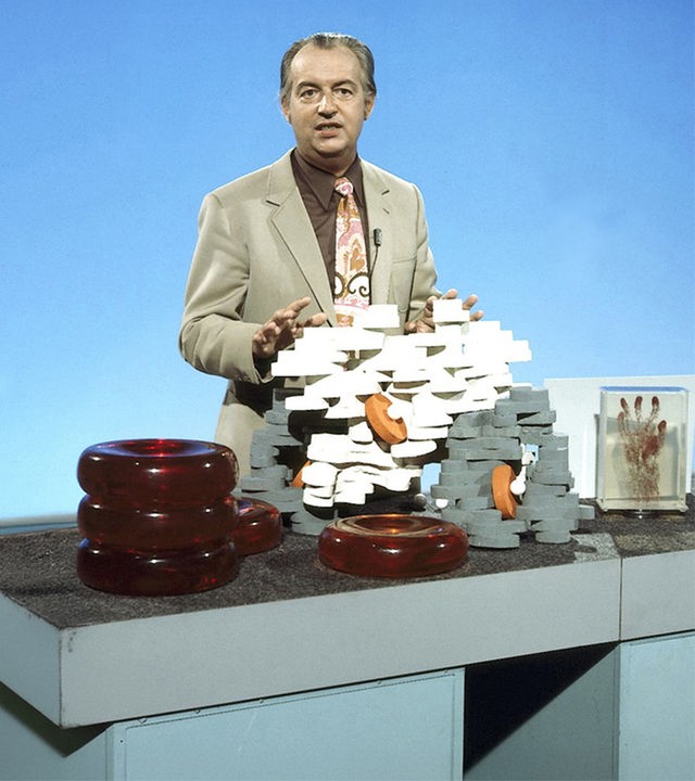 Farbfoto von Hoimar von Ditfurth, der vor einem Tisch steht