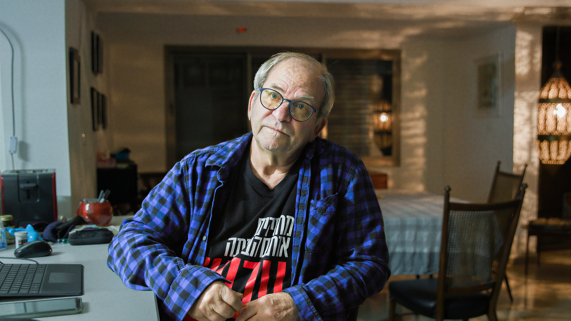 Mann sitzt seitlich an einem Schreibtisch mit einem geöffneten Laptop.