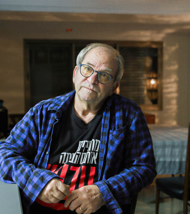 Mann sitzt seitlich an einem Schreibtisch mit einem geöffneten Laptop.