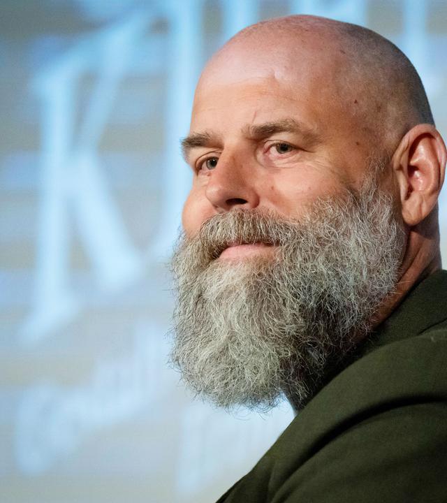 Ein Mann mit Glatze trägt einen Bart.