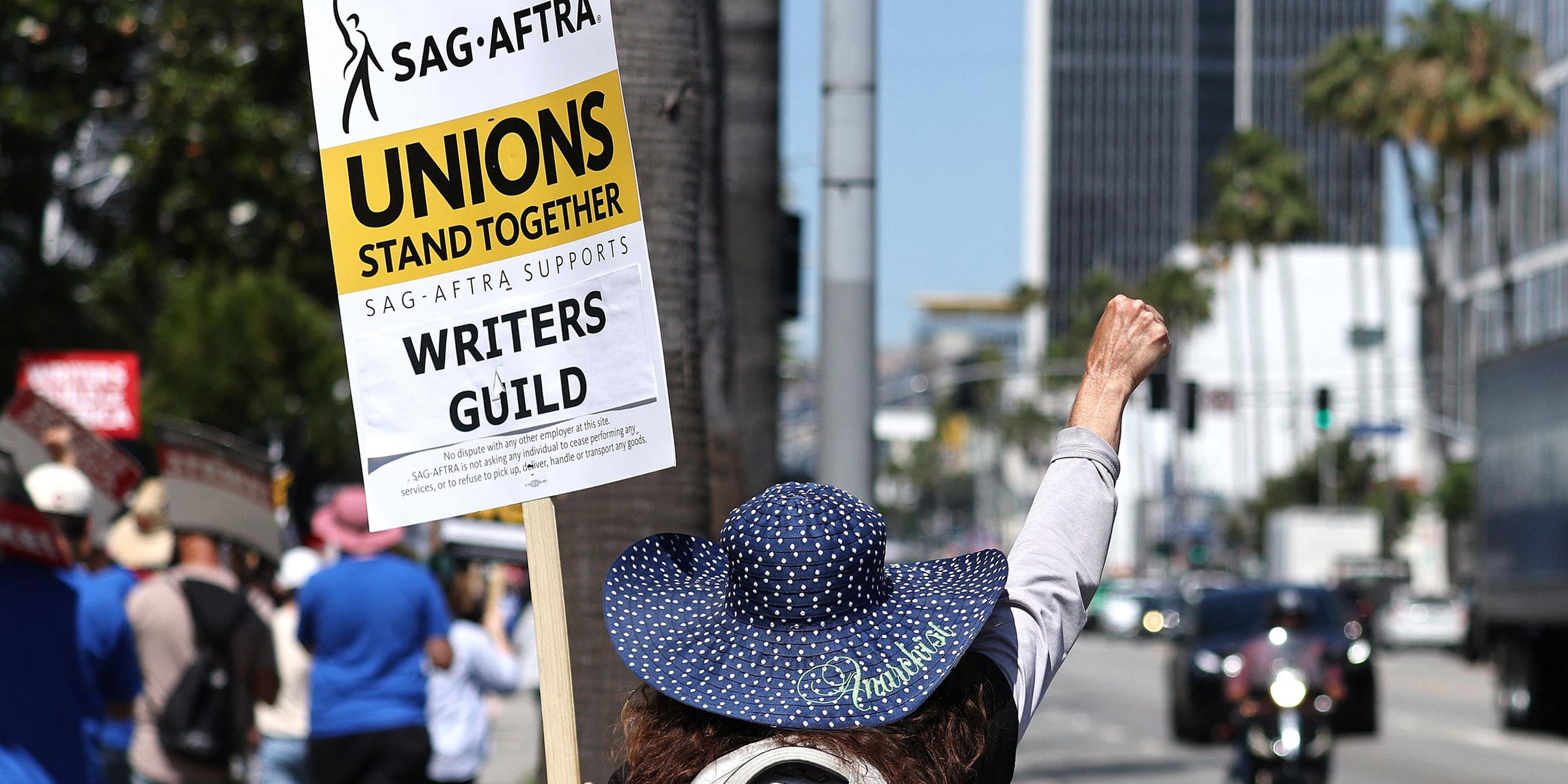 Eine Frau demonstriert auf ihrem Schild steht „Gewerkschaften stehen zusammen“. (12.07.2023)