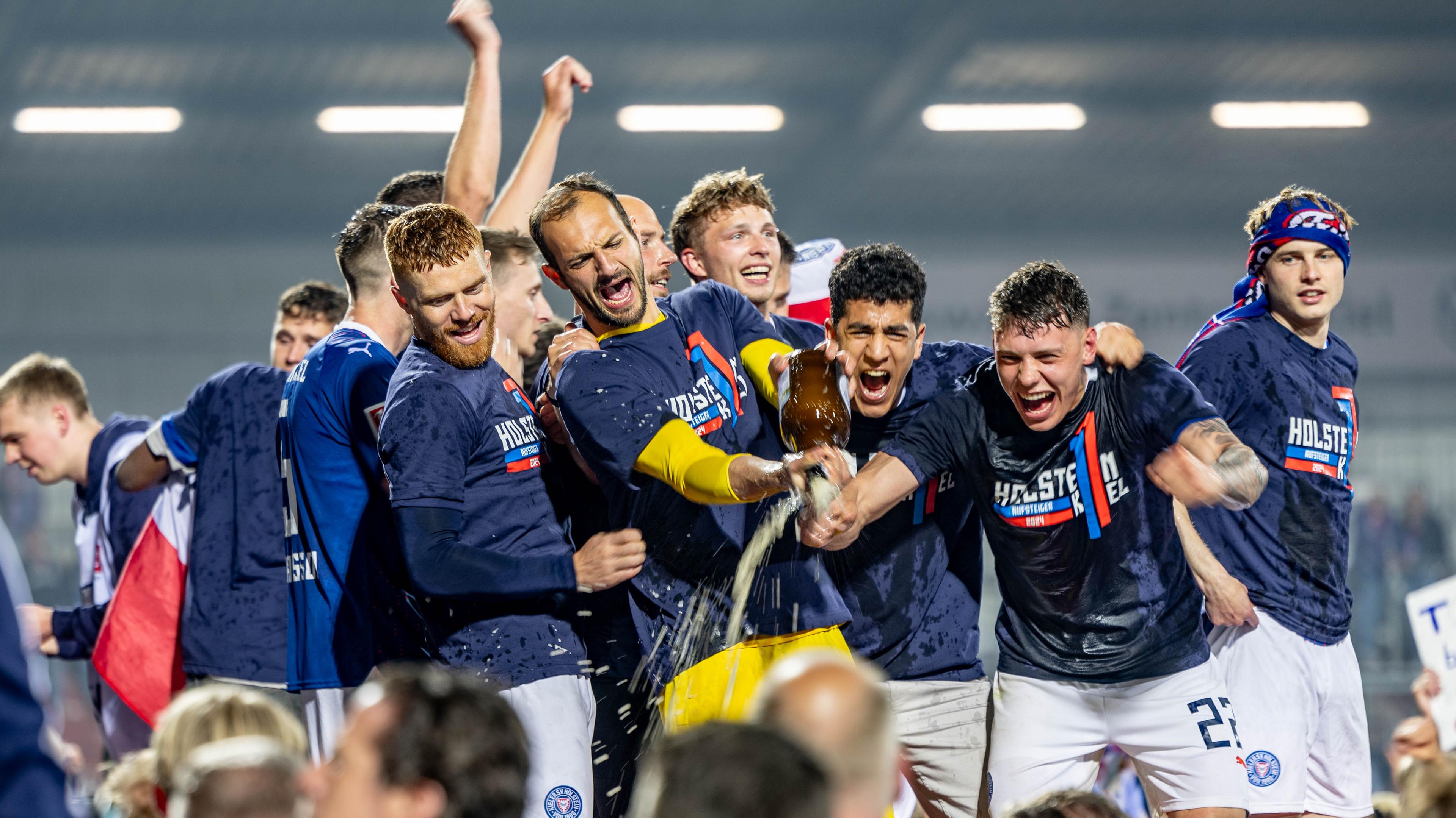 Die Spieler von Holstein Kiel feiern mit den Fans gemeinsam den Aufstieg.