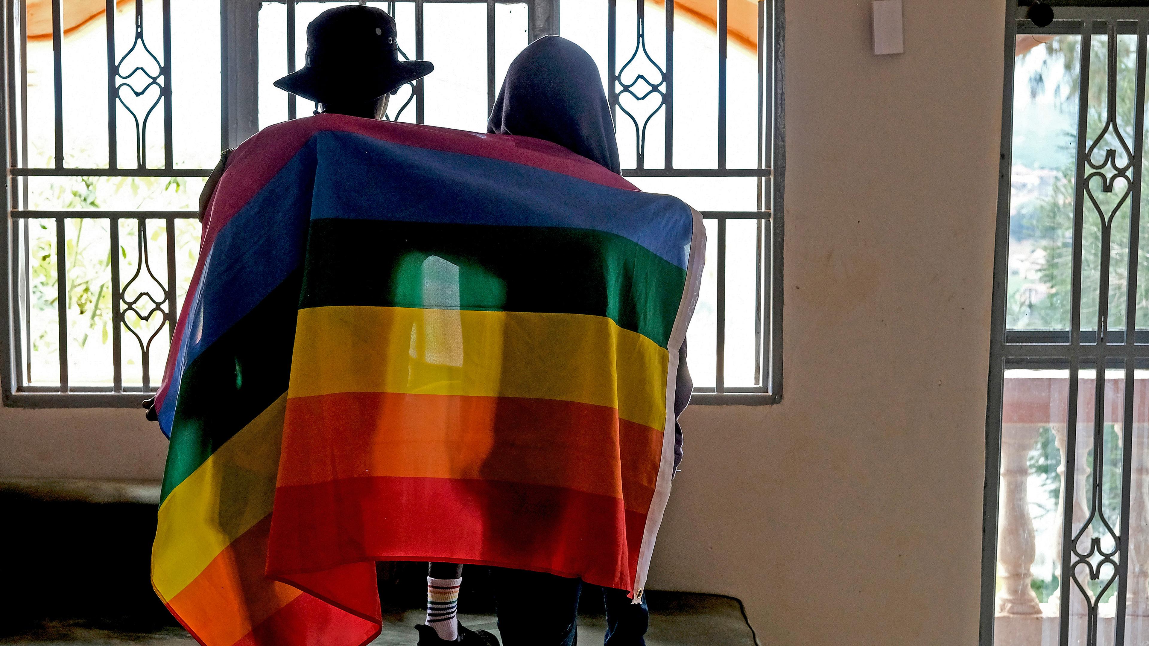 Schwules ugandisches Paar bedeckt sich mit einer Regenbogenfahne, aufgenommen am 25.03.2023