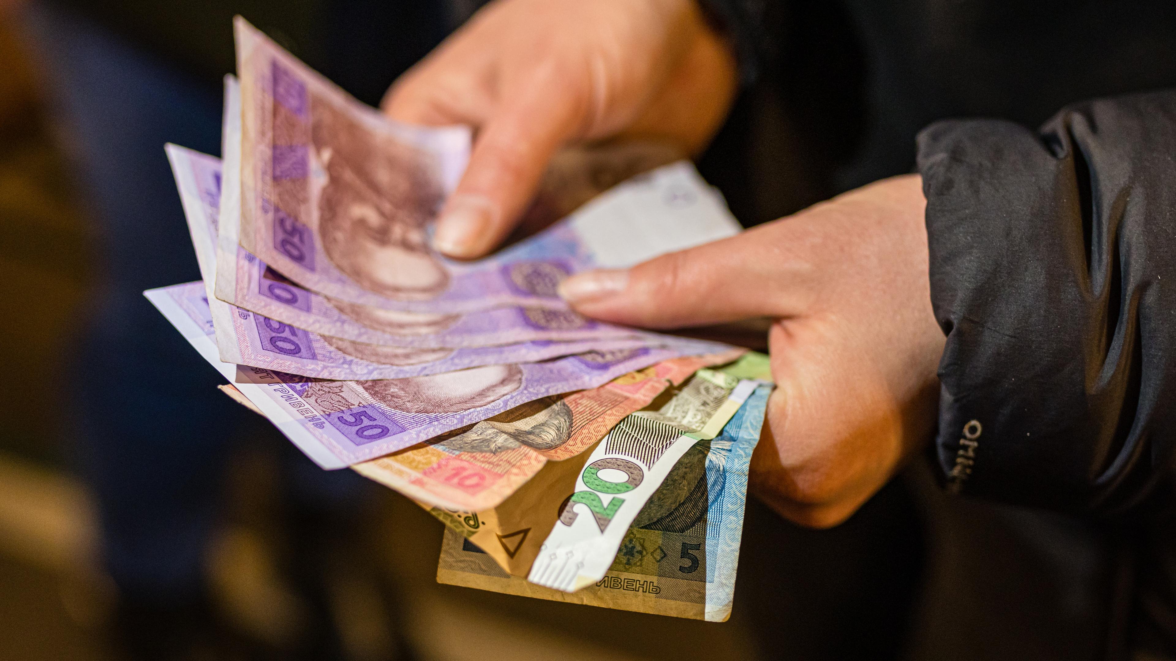 Eine Person hält ukrainische Geldscheine