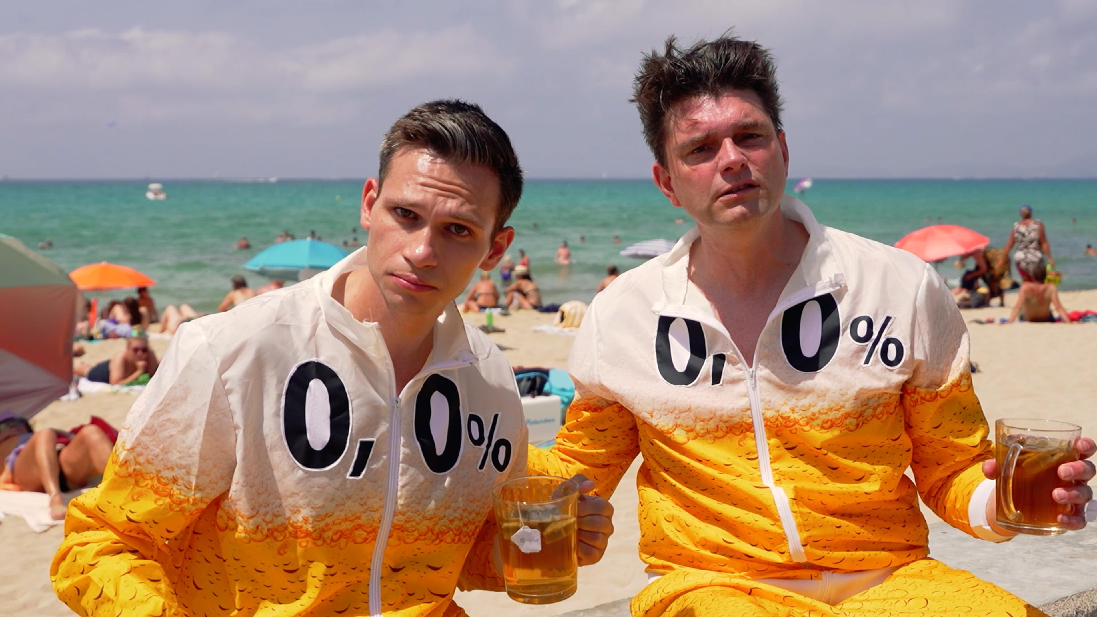 "heute-show spezial": Fabian Köster und Lutz van der Horst an der Strandpromenade auf Mallorca. Sie tragen Trainingsanzüge mit dem Aufdruck "0,0 %".