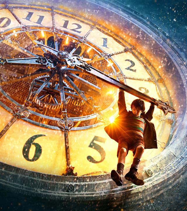 Plakatmotiv zum Film mit Asa Butterfield. Hugo hängt mit beiden Armen am Zeiger der großen Uhr des Pariser Bahnhofs.