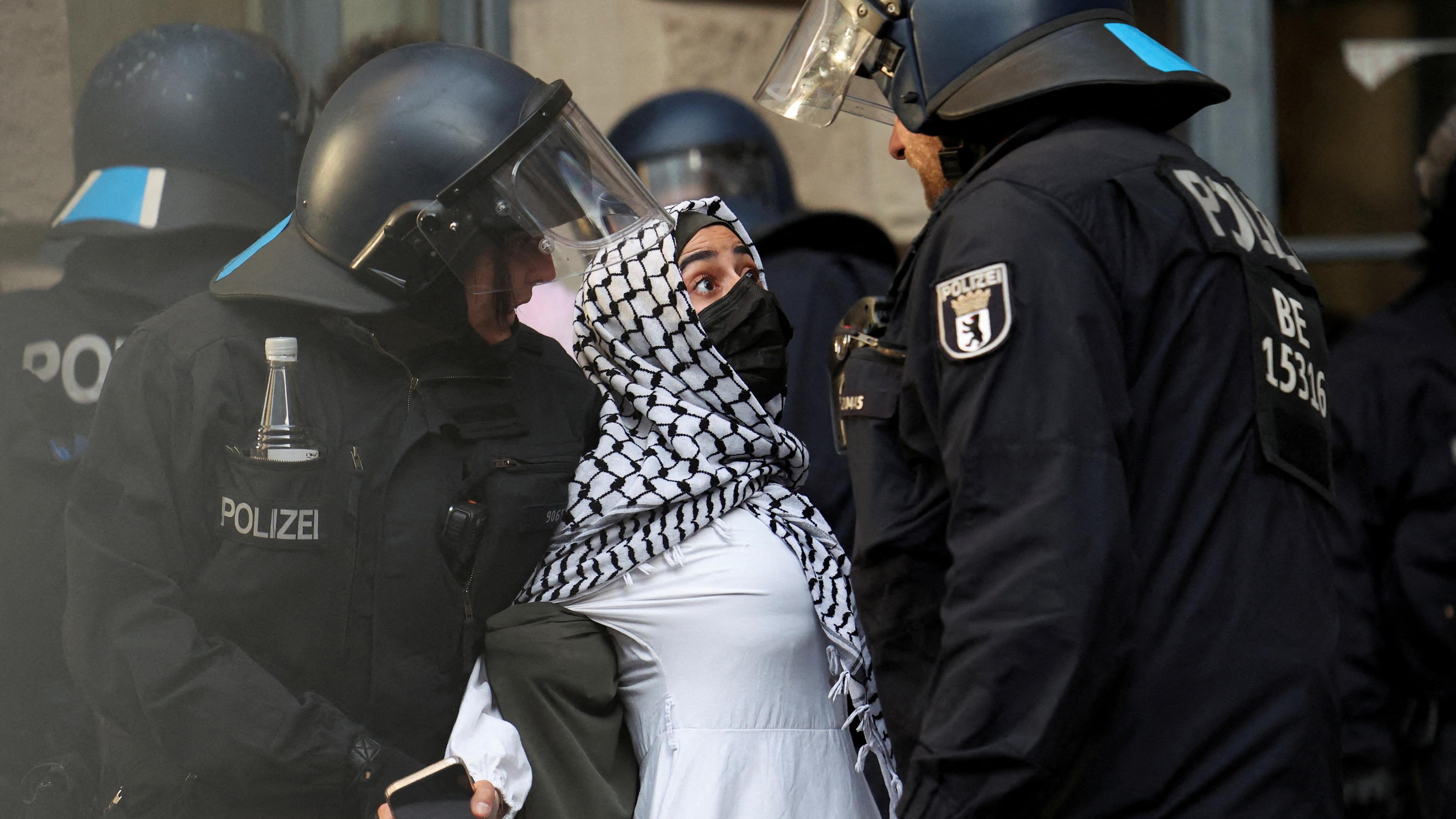 Eine junge Frau wird von zwei Polizisten festgehalten.