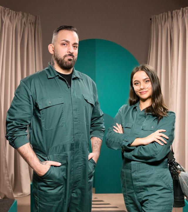 Die Gäste der Sendung stehen in grünen Overalls vor der Kamera.