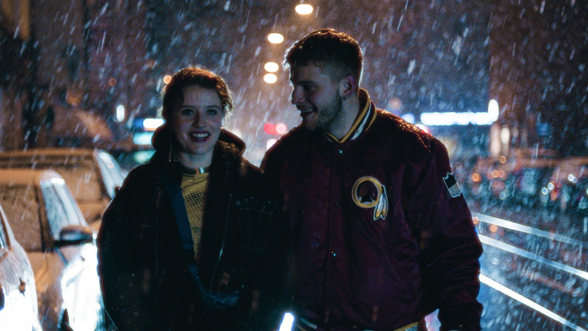 "I AM THE GREATEST - Weil ich ein Kind der Sonne bin": Marie (Katharina Stark) und Gabriel (Ben Felipe) laufen durch die regnerische Nacht und lächeln sich an.