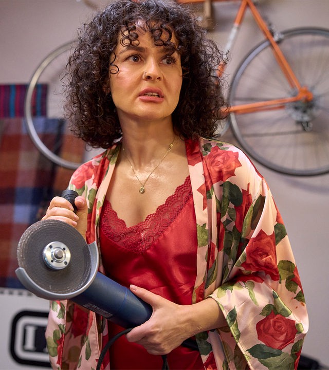"Ich dich auch! - Der Stichtag": Jackie (Nagmeh Alaei) steht im Spitzennachthemd völlig aufgelöst im Raum. Sie hält eine Schneidemaschine in den Händen.