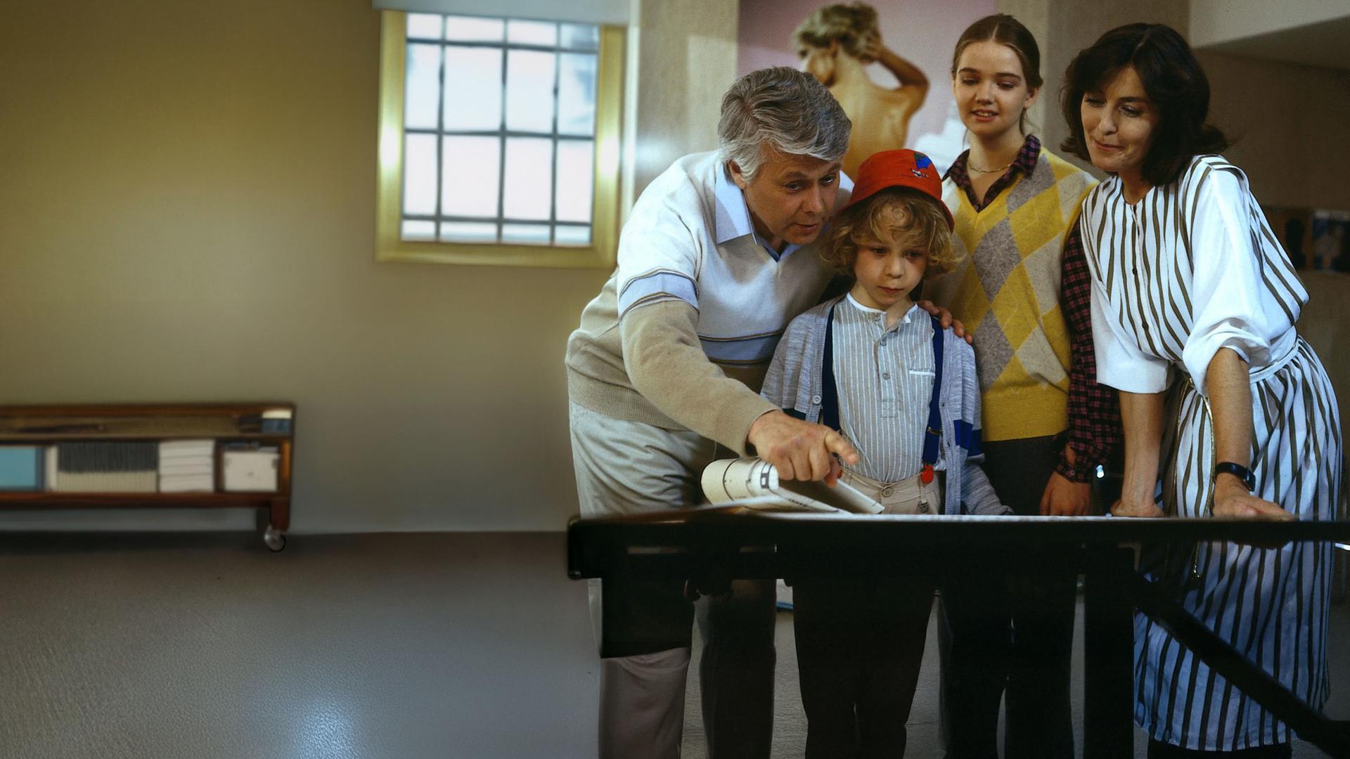 Angelika und Werner stehen mit den Kindern Tanja und Markus zusammen. Sie schauen lächelnd in dieselbe Richtung, während Werner mit seinem Finger auf etwas in derselben Richtung zeigt.