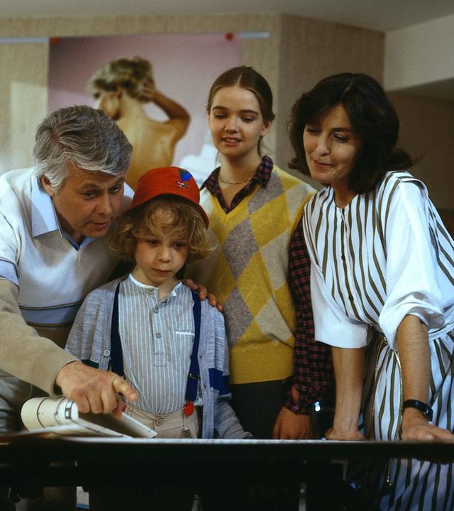 Angelika und Werner stehen mit den Kindern Tanja und Markus zusammen. Sie schauen lächelnd in dieselbe Richtung, während Werner mit seinem Finger auf etwas in derselben Richtung zeigt.