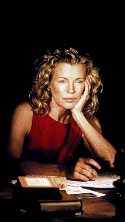 Kim Basinger sitzt am Schreibtisch