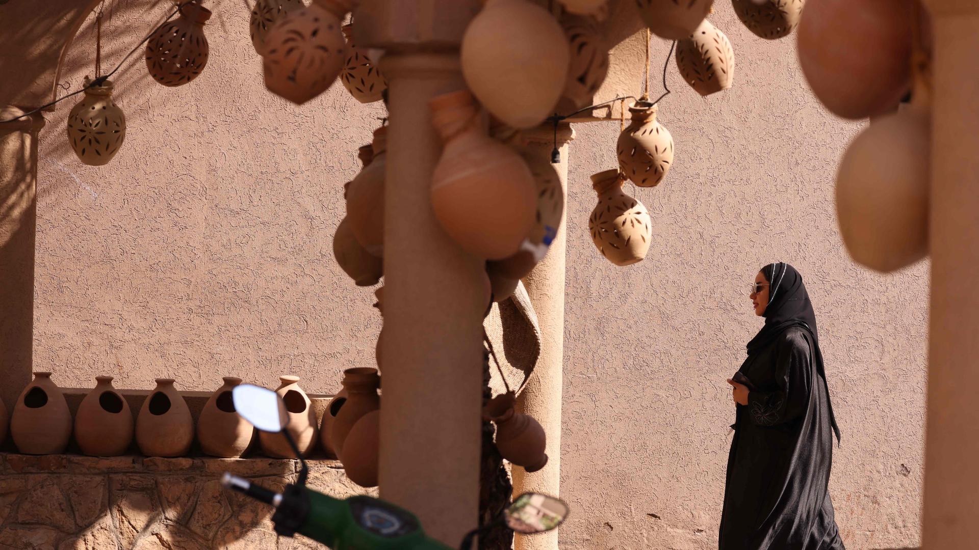Eine Frau, in schwarz gekleidet, besucht den Nizwa-Marktplatz im Oman.