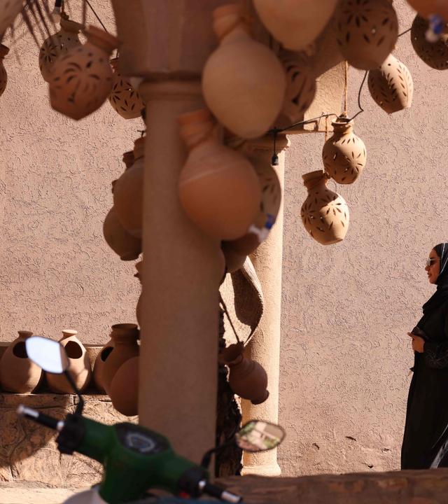 Eine Frau, in schwarz gekleidet, besucht den Nizwa-Marktplatz im Oman.