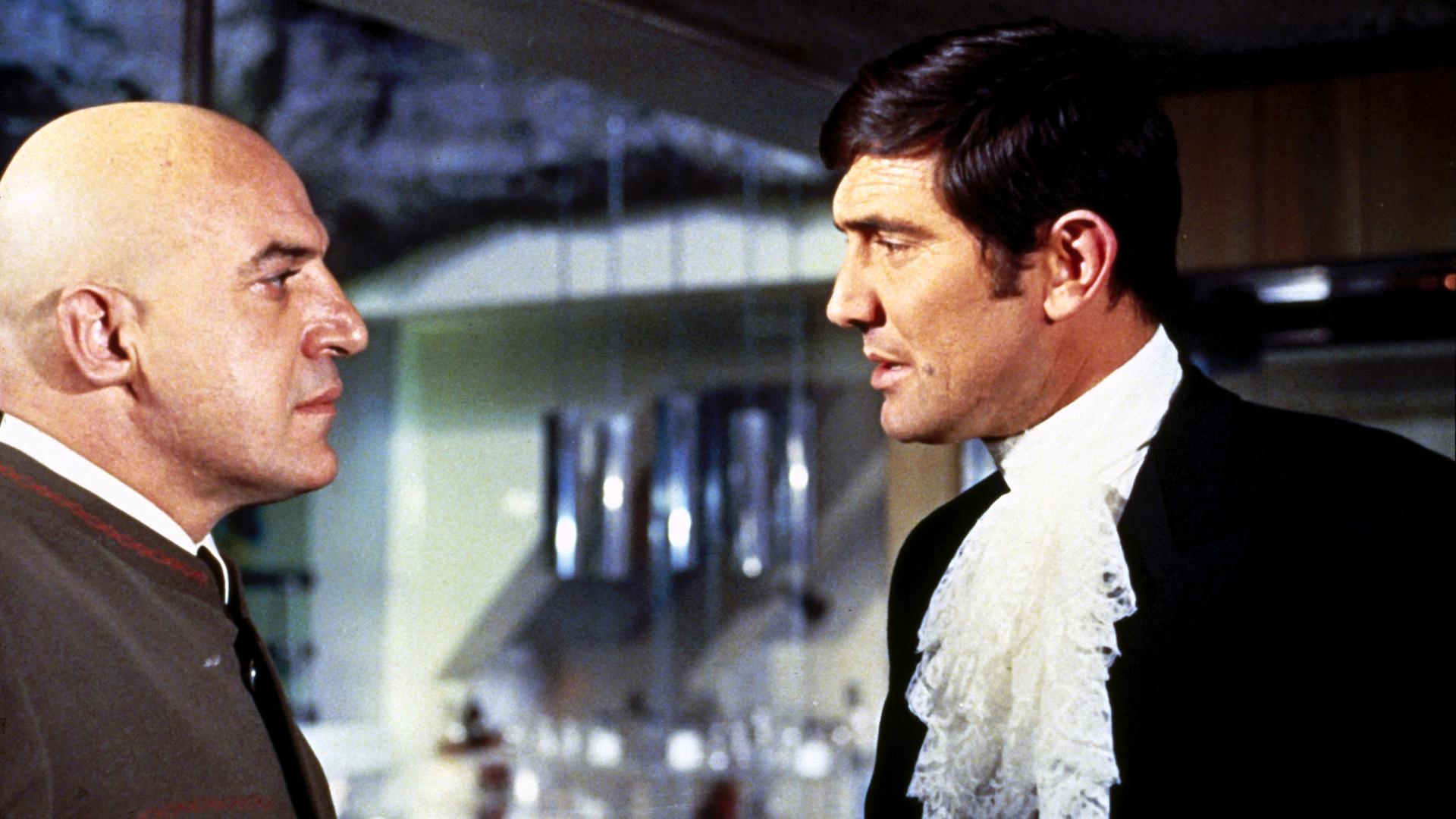 Agent 007 (George Lazenby) steht Blofeld (Telly Savalas) gegenüber und schaut ihn eindringlich an.