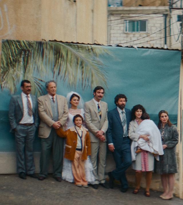 Gruppe Menschen steht vor einem Bild mit Palmen