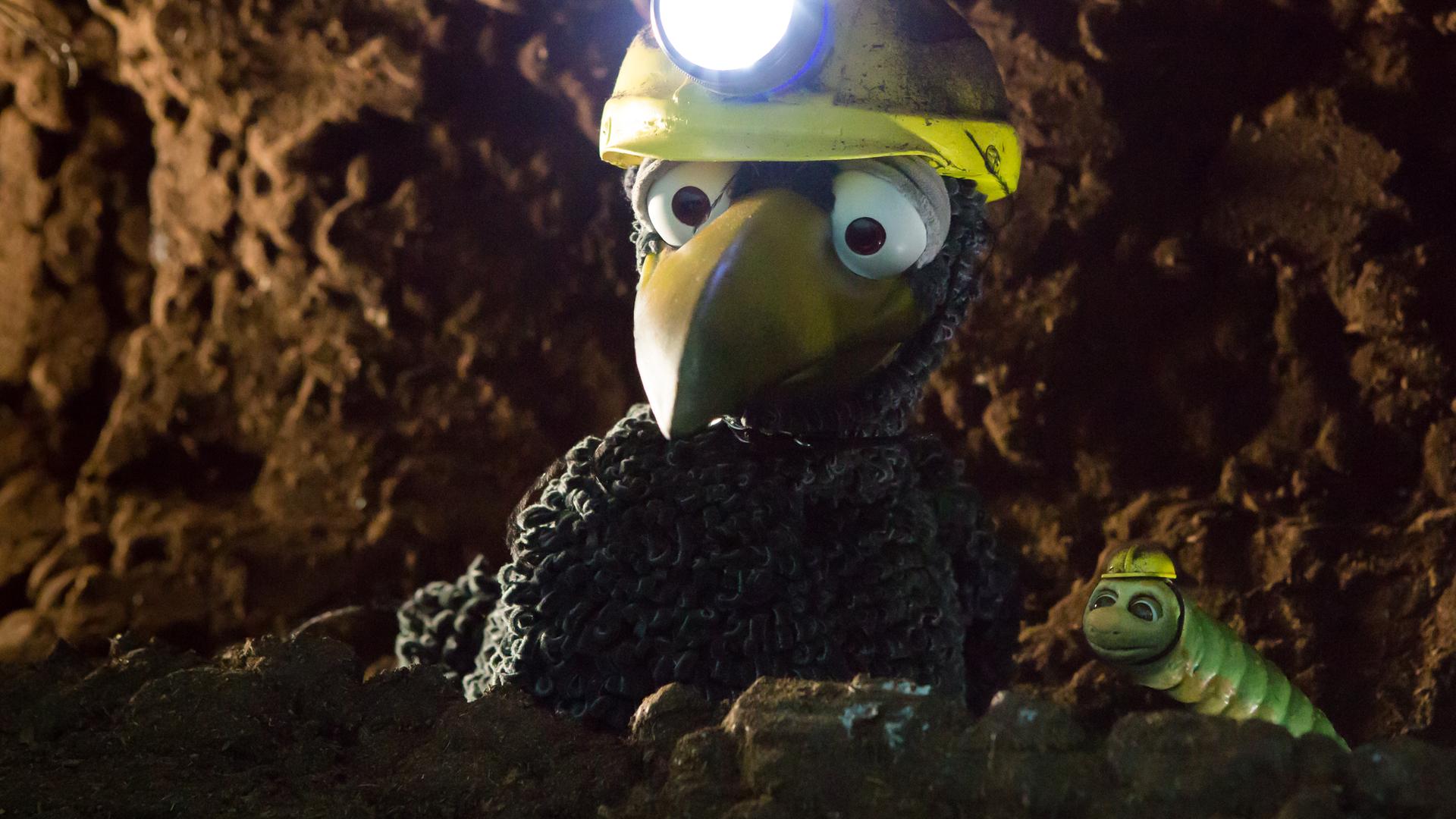 Rabe Rudi und Wurm Lotti sitzen in Gretes Tunnel. Rudi hat eine Stirnlampe auf.