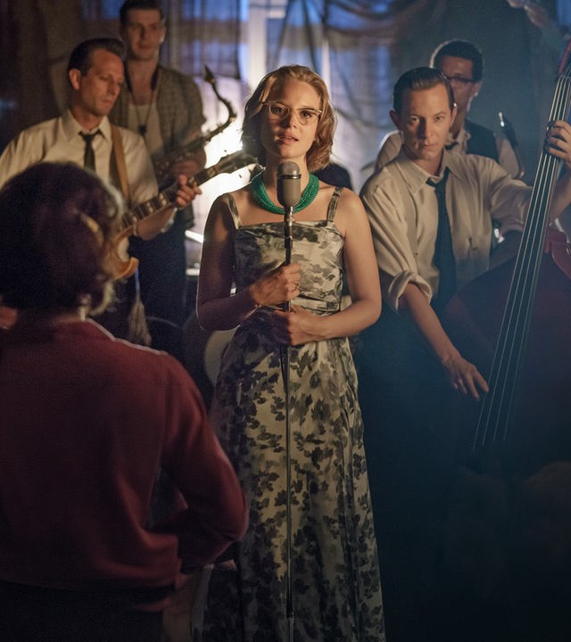 Monika Schöllack (Sonja Gerhardt) steht auf einer Bühne und singt, während Freddy Donath (Trystan Pütter) etwas hinter ihr Kontrabass spielt. Weitere Musiker stehen hinter den beiden.