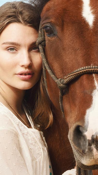 Lou (Leia Holtwick) lehnt ihren Kopf an den eines Pferdes.