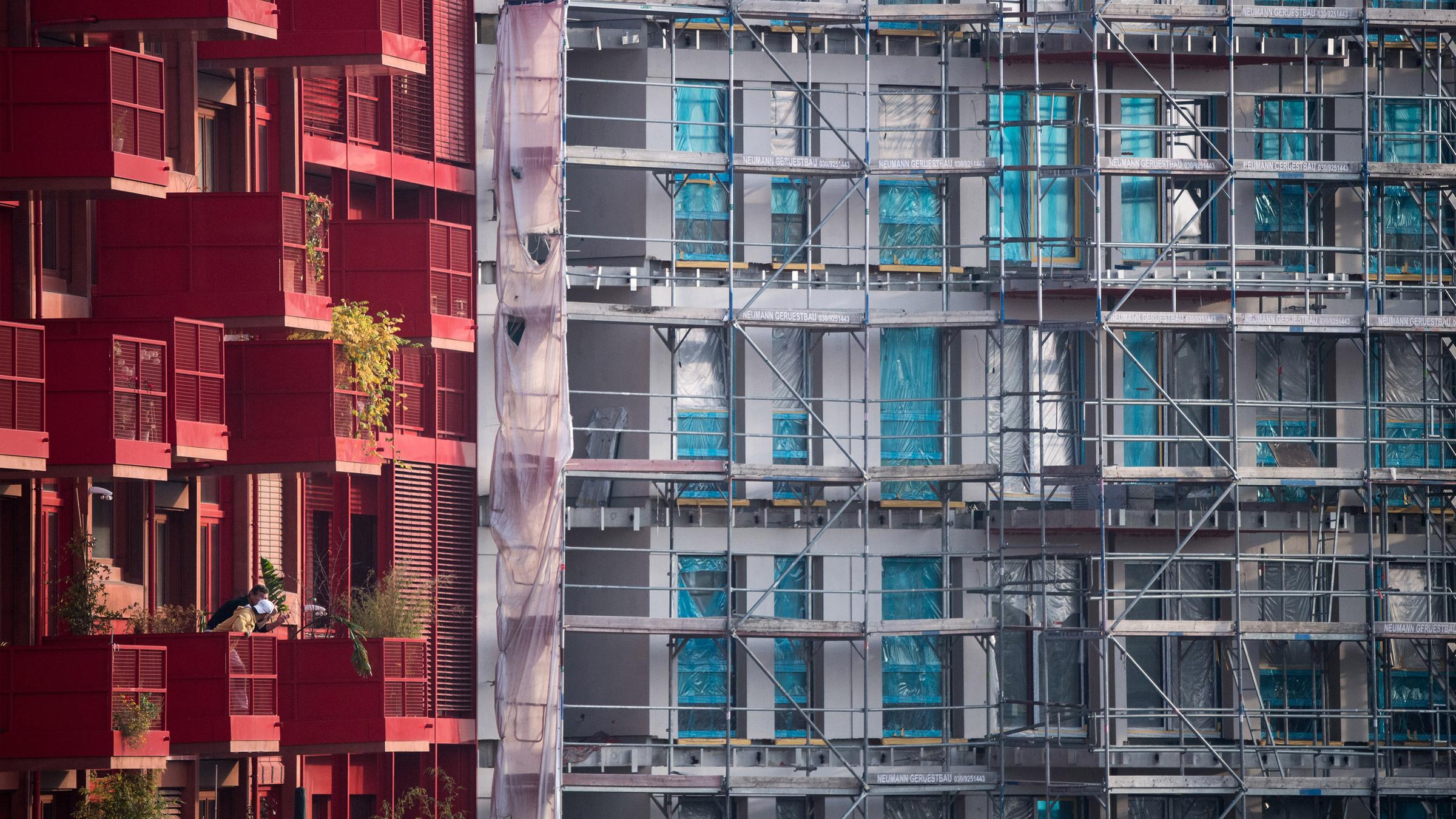 Archiv: Ein Baugerüst steht an einem Rohbau neben bereits fertiggestellten Neubau-Wohnungen in Berlin Kreuzberg.