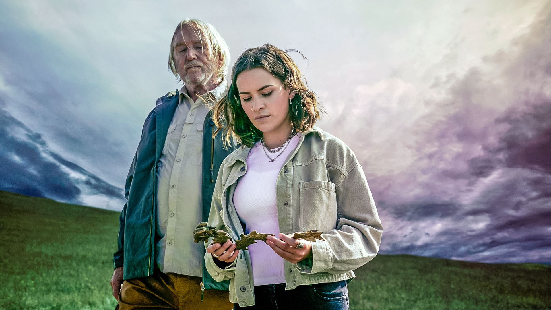 Issie steht neben ihrem Großvater Gordon, der mit starren Blick auf die goldene Drachenfigur schaut, die Issie in ihren Händen hält. Um sie herum beginnt ein Unwetter aufzuziehen.