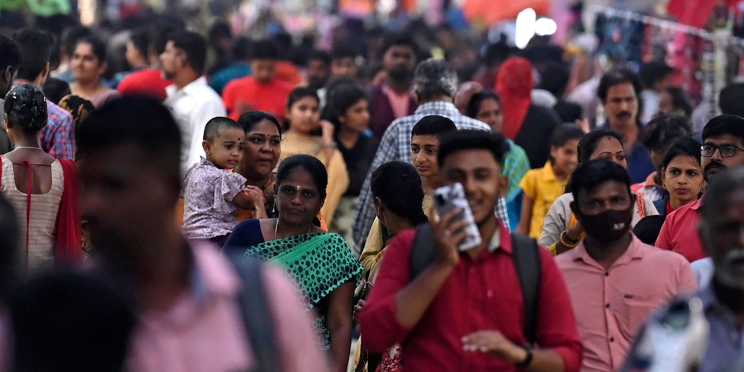 Menschen gehen durch eine überfüllte Geschäftsstraße in Chennai, Indien.