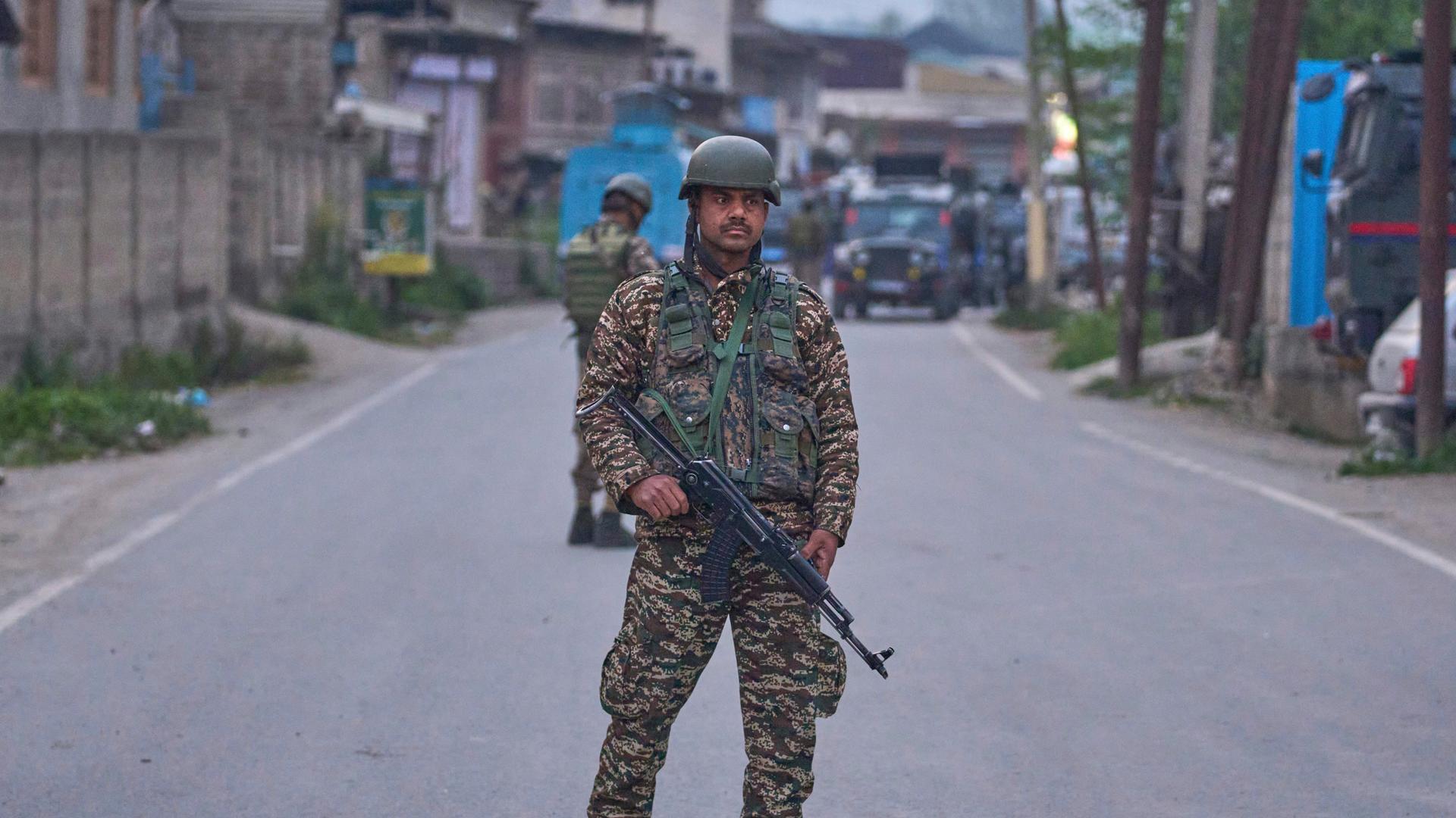 Soldat mit Maschinengewehr und in Uniform steht auf Straße.