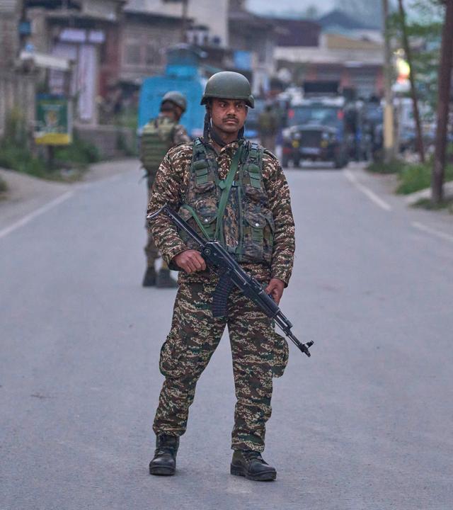 Soldat mit Maschinengewehr und in Uniform steht auf Straße.