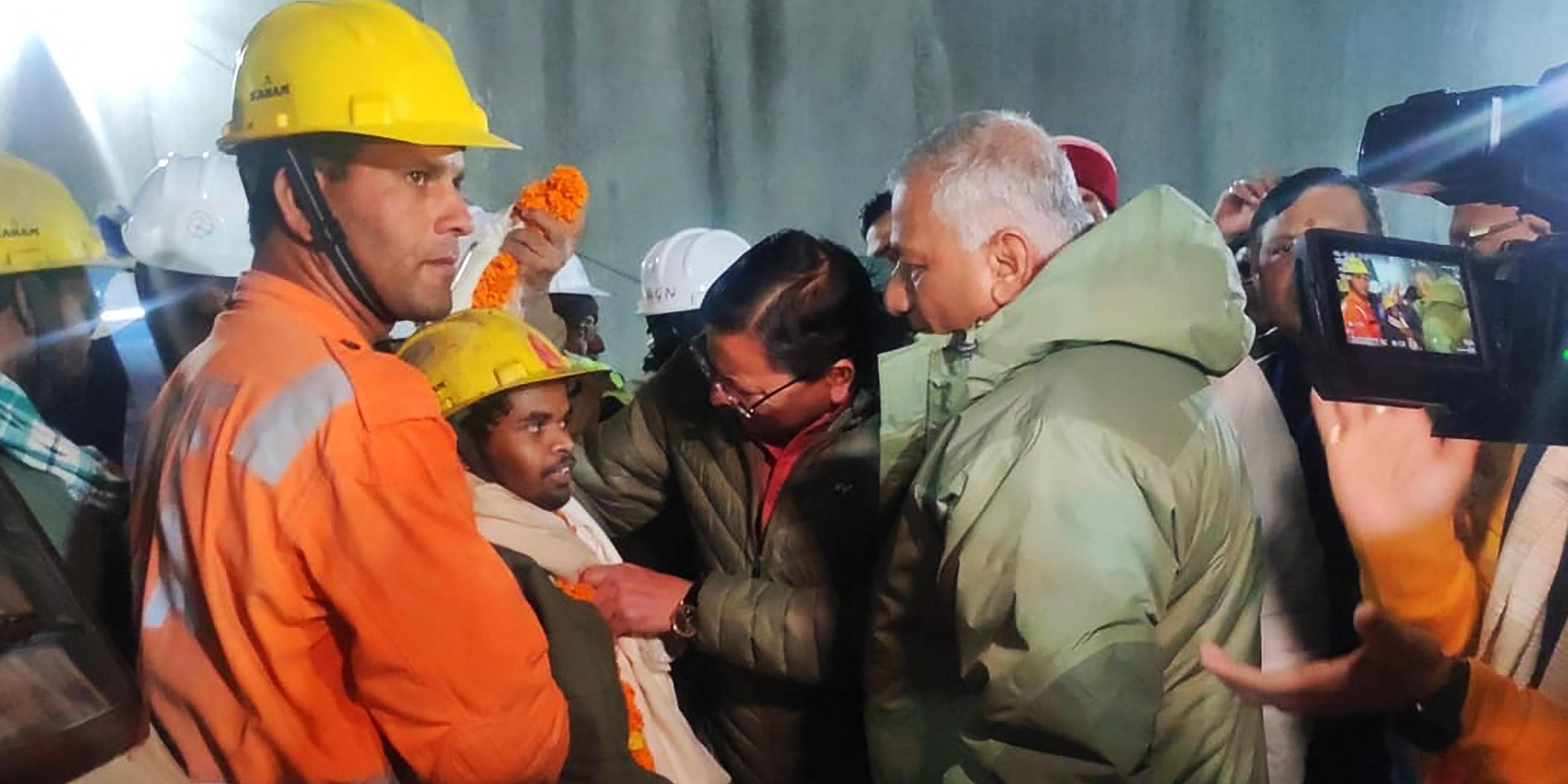 Indien: Bauarbeiter (vorne 2l) im Dialog mit dem Ministerpräsidenten von Uttarakhand, Pushkar Singh Dhami (Mitte), nach seiner Rettung aus dem Untergrund Bau des Silkyara-Tunnels.