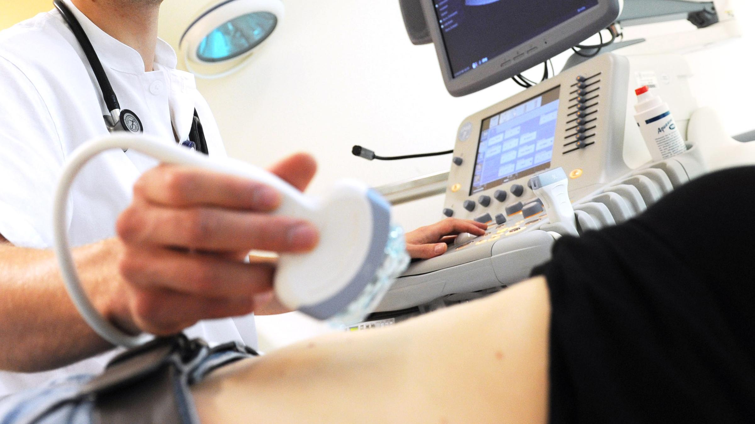 Ein Mediziner untersucht eine Frau mit einem Ultraschall-Gerät.