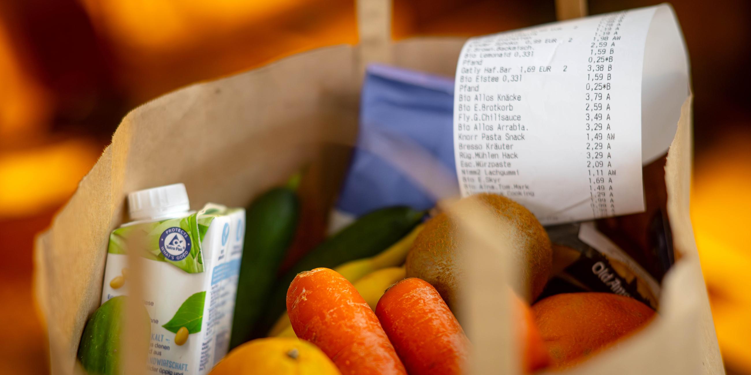 Ein Kassenbon liegt auf den Lebensmitteln in einer Einkaufstüte.
