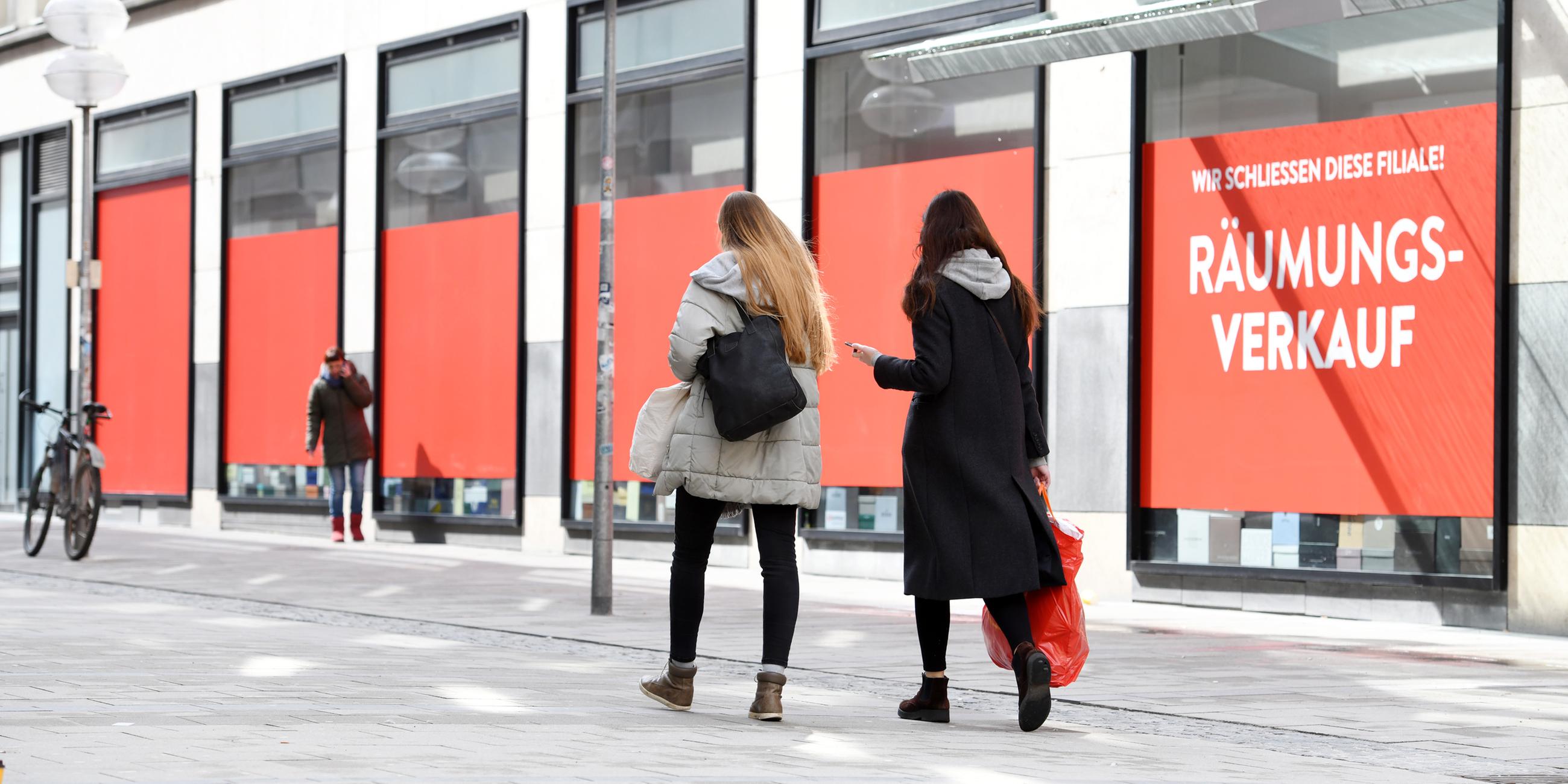 Zwei Frauen gehen in der Münchner Innenstadt an abgehänten Schaufenstern vorbei.